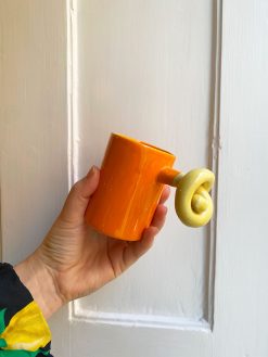 Orange keramikkop med knudehank i lysegul. Koppen er håndlavet i Tyrkiet hos Zoks Studio.