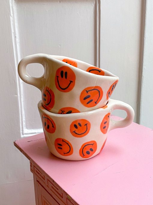 håndlavet keramikkop fra Posy Keramik med orange smiley'er. smiley Koppen er håndlavet i Tyrkiet af Australske Emily.
