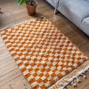 Ternet tæppe fra Marokko. Tæppet er håndlavet kommer med orange og hvide tern og er lavet i 100% uld.