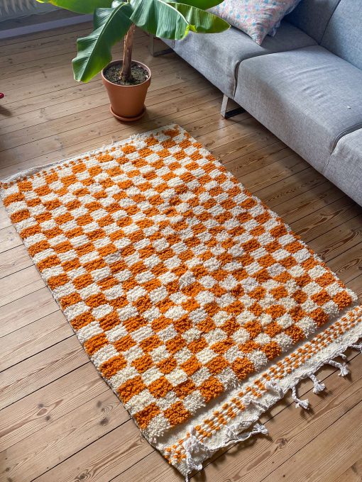 Ternet tæppe fra Marokko. Tæppet er håndlavet kommer med orange og hvide tern og er lavet i 100% uld.