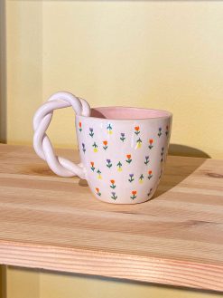 Flower mug with small mini flowers in different colors. The mug has a twisted handle, is white on the outside and pink on the inside. Handmade in Turkey by Winged Pupa.