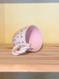 Flower mug with small mini flowers in different colors. The mug has a twisted handle, is white on the outside and pink on the inside. Handmade in Turkey by Winged Pupa.