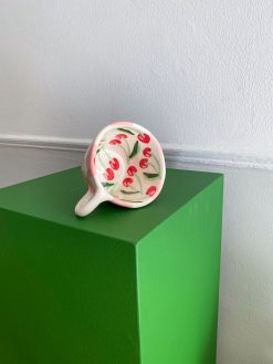 Ternet kop med hank og røde kirsebær nede i koppen. Håndlavet af Posy Ceramics.