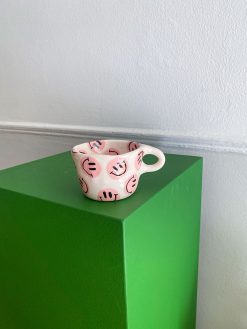 smileykop med hank med lyserøde smileys udenpå og nedeni. Håndlavet af Posy Ceramics.